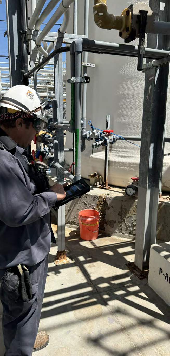 Operator using a tablet beside plant equipment during a field round.